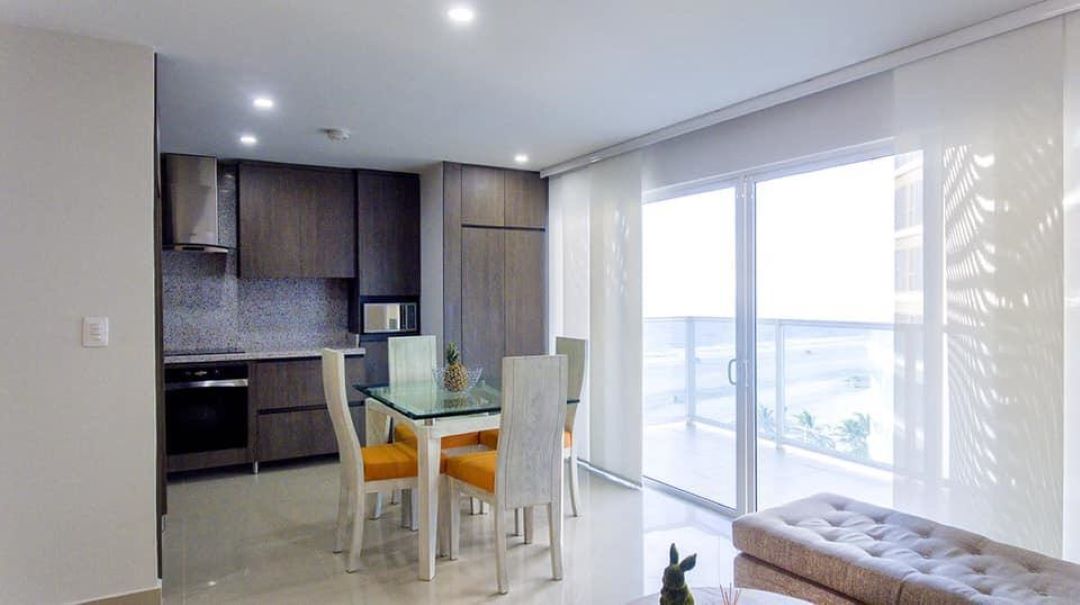 zona comedor con mesa y sillas para 4 personas, cocina abierta estilo moderno y amplio balcón con vista al mar de Cartagena