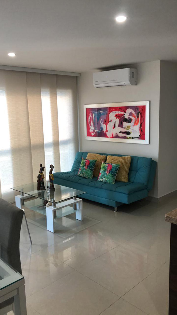 sala de estar en apartamento para alquiler en Cartagena, equipada con sofacama y mesa de café en vidrio y metal