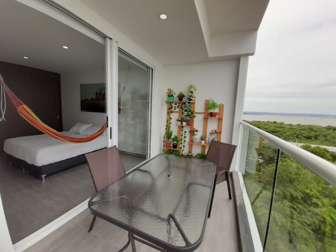 desde el balcón de un apartamento en Cartagena se puede ver la habitación principal equipada con cama doble y hamaca