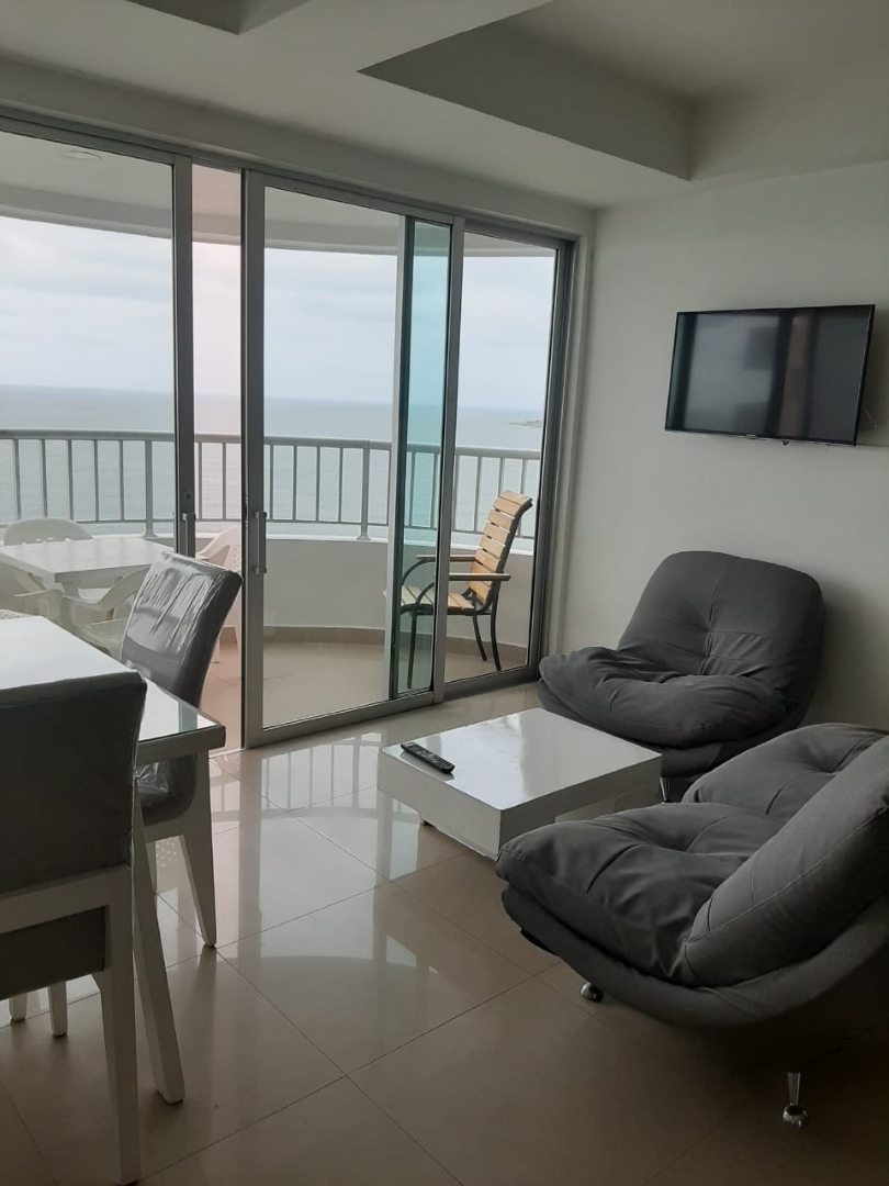 sala de estar en apartamento de Cartagena con sofá, poltrona, mesa de café y salida a balcón amoblado con vista al mar