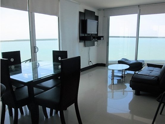 sala comedor con pisos en ceramica color gris claro y sillas en cuero color negro mesa en vidrio y televisor
