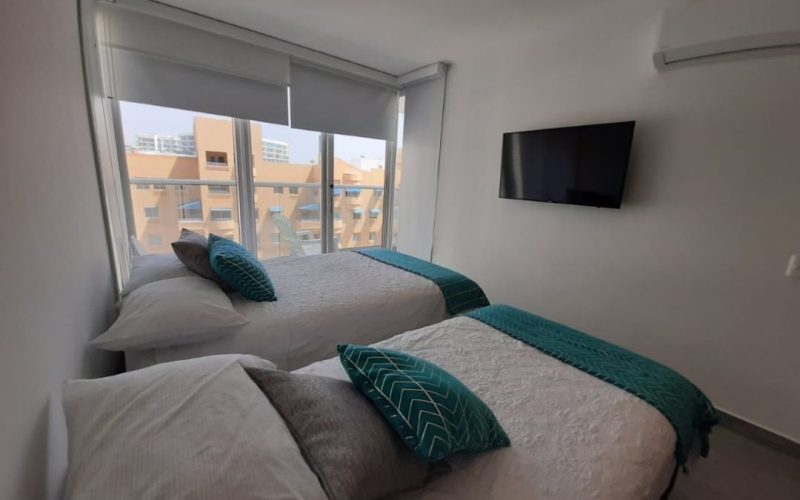 amplia habitación equipada con cama doble, cama sencilla y tv, con vista exterior a la Zona Norte de Cartagena