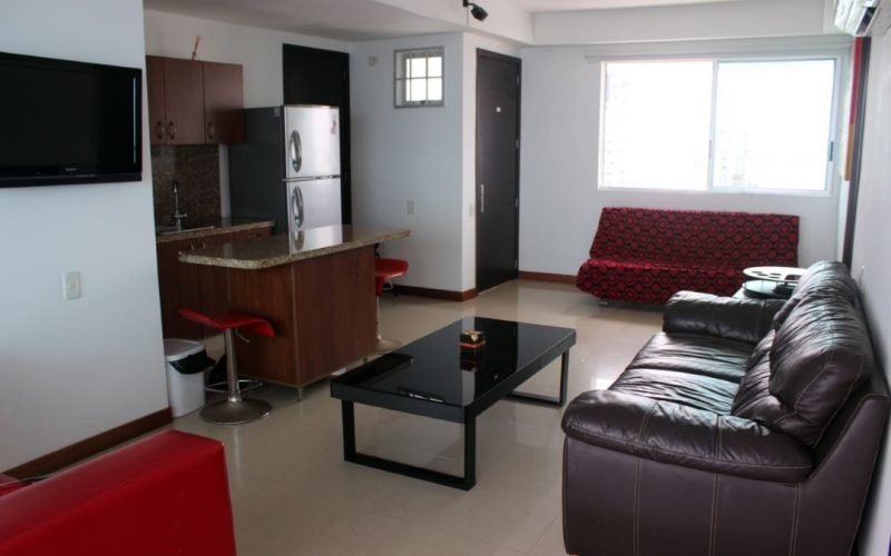 vista de apartamento con sala de estar de 2 sofás y cocina abierta con comdero tipo isla y butacas para 2 personas
