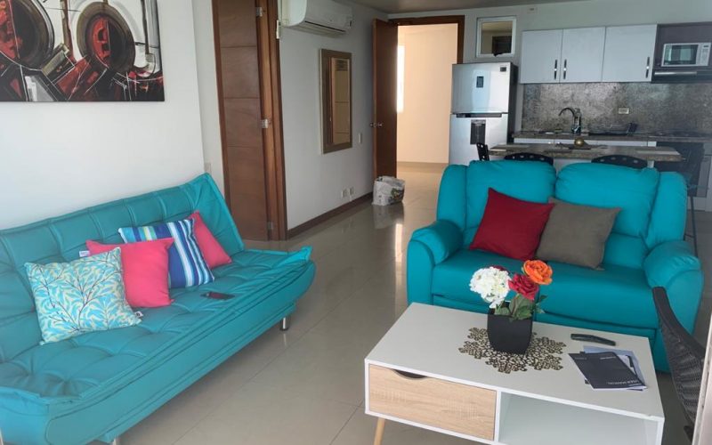 sala de estar con sofás, mesa de café y cocina tipo americano con electrodomésticos en apartamento de Cartagena