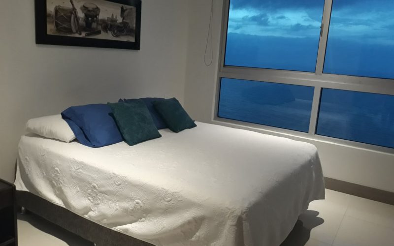 habitacion con cama doble, almohadas de colores y vista al mar en cartagena