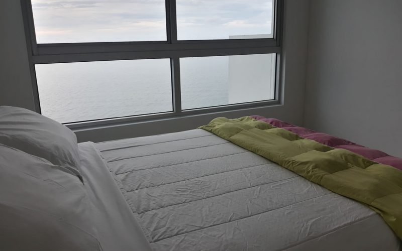 habitacion con cama doble y sabanas blancas con vista al mar