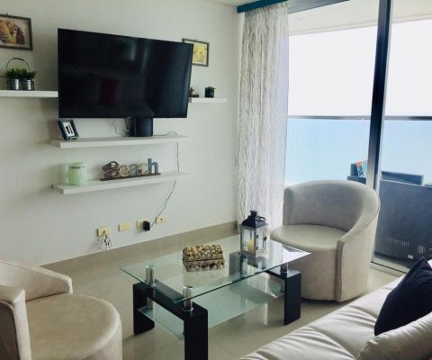 sala de estar en apartamento, 2 sillas, sofá y mesa de café acompañan la decoración moderna, ventanal con vista al mar