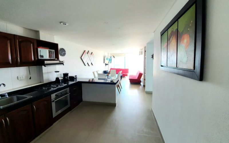 vista desde cocina de apartamento para alquiler por dias en laguito cartagena al fondo comedor blanco y sala con sillas rojas